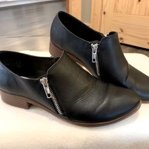 Black loafer with zipper detail on both sides.